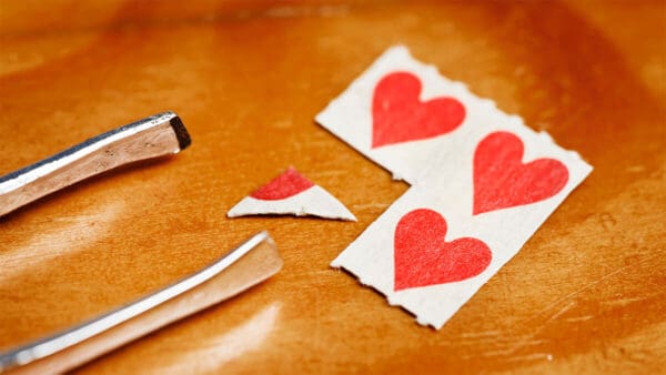 tabs of LSD with hearts, divided into fourths with a pair of tweezers