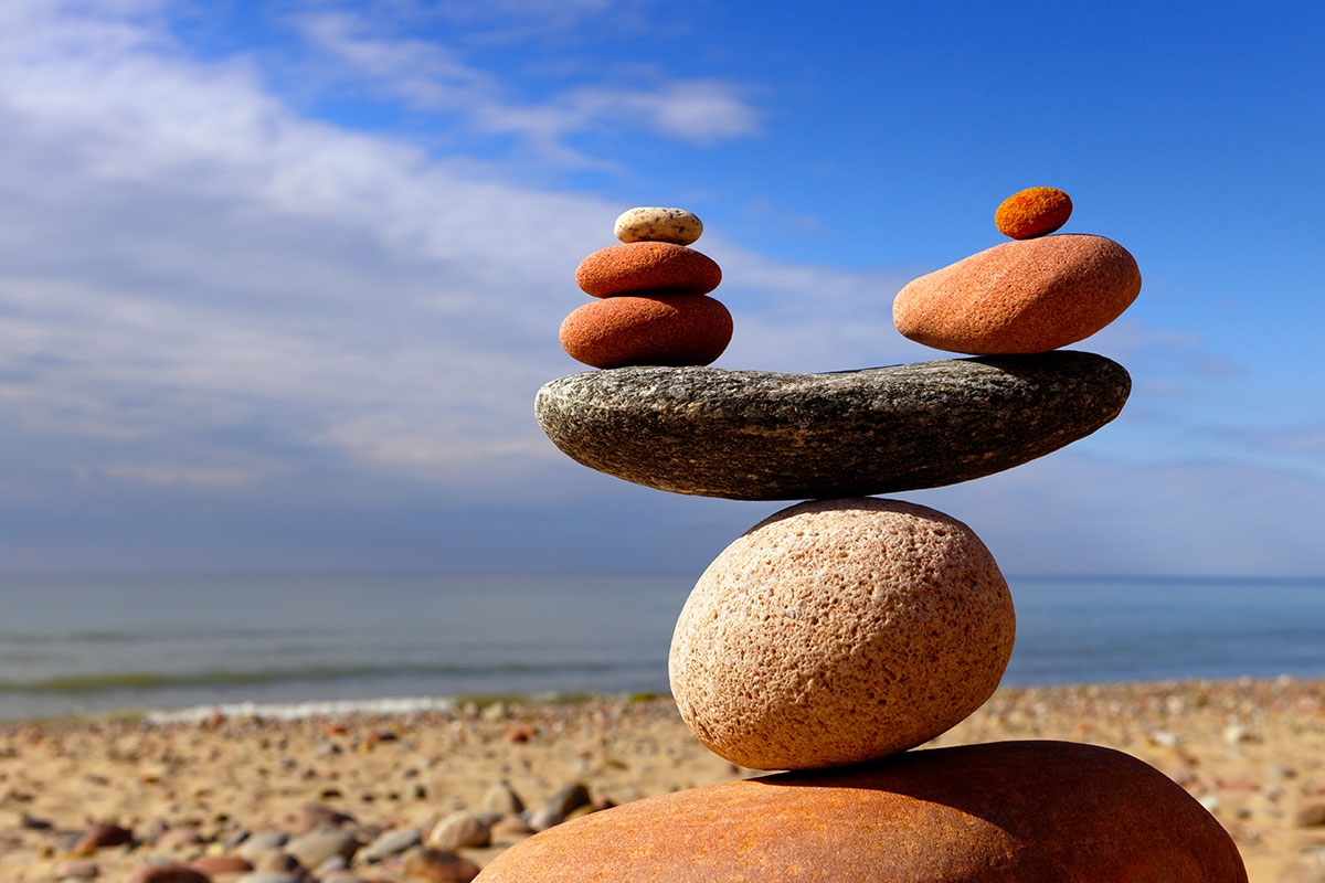 a pile of stones creates a balance with ocean and sand view in background