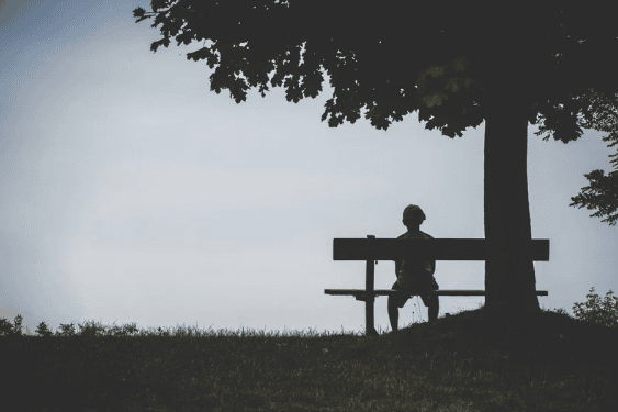Man sitting alone on a bench, gazing into the distance, reflecting on his healing journey.