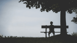 Man sitting alone on a bench, gazing into the distance, reflecting on his healing journey.